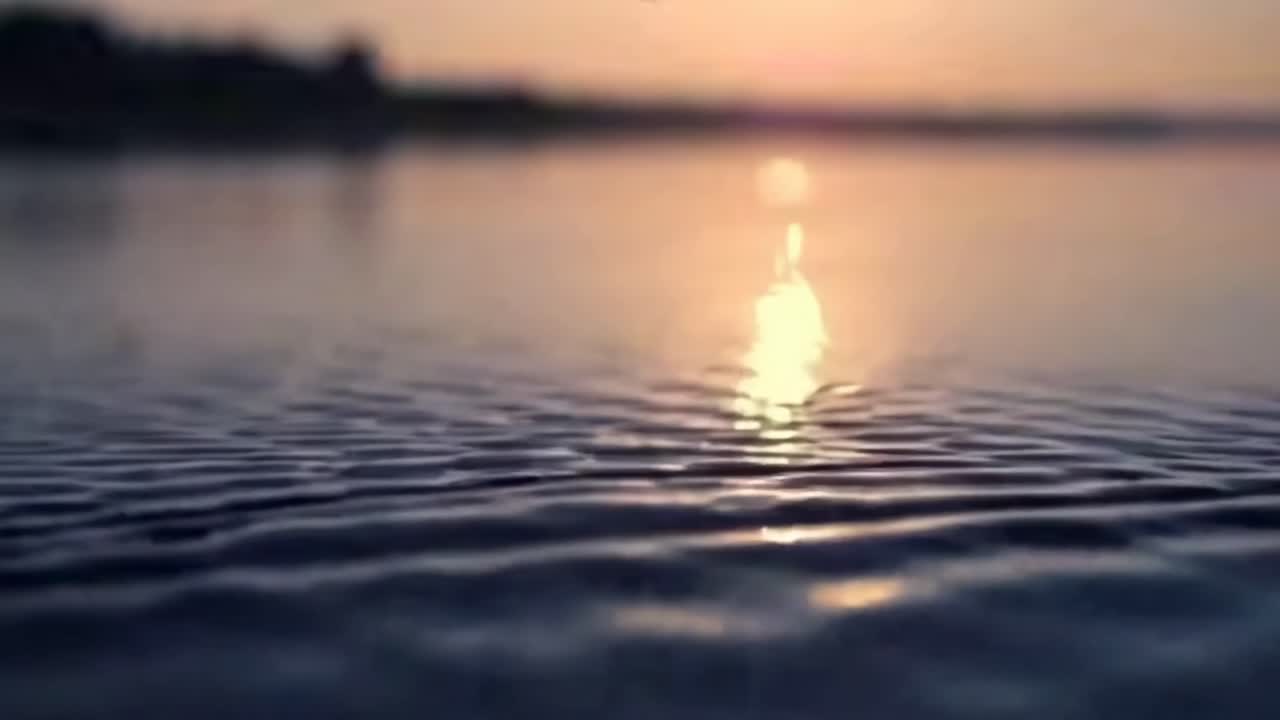 Serene sunset over rippling water, captured in a low-angle video for a tranquil effect