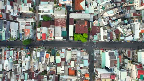aerial-top-down-shot-flying-forward-crossing-the-perpendicular-intersection-as-motorbikes-drive-the-narrow-roads-of-Ho-Chi-Minh-City-Vietnam-surrounded-by-local-residential-buildings