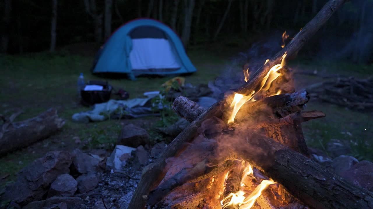 Panning in front of a campfire as the flaming woodfire gives off smoke that could ward off some insects at night, at a campsite on Strandzha Mountain in Bulgaria