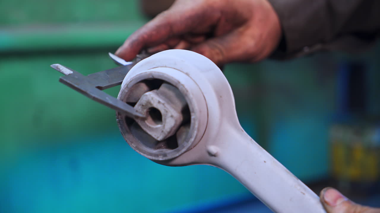 Turner's hand measuring the ready made detail with calipers. Turner in his workshop. Close up. Blurred backdrop.