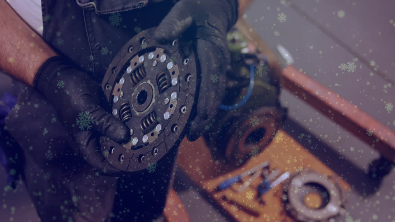 Gloved hands holding circular clutch disc in automotive workshop, with animated gear icons rotating