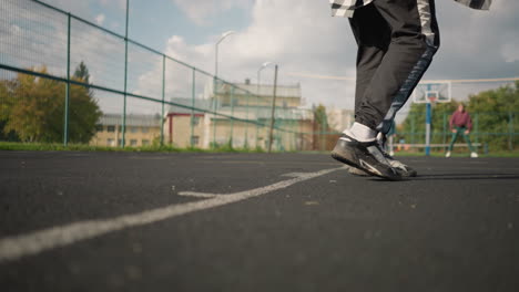 close-up leg view of athlete wearing sneakers and joggers running forward on track with blurred background of people standing, showcasing athletic movement and footwear