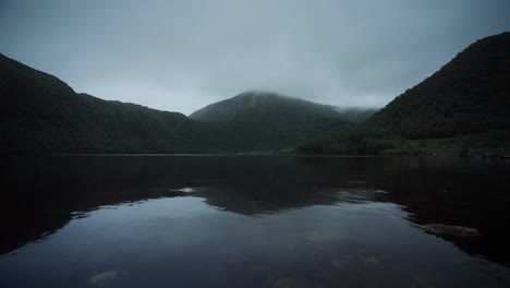 mountain range under overcast sky reflecting in the water of the lake