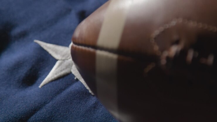 Enfoque que se desplaza de un primer plano de fútbol americano a la bandera de barras y estrellas 1