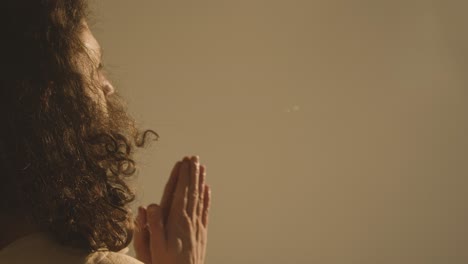 retrato de un hombre con cabello largo y barba que representa la figura de jesucristo poniendo las manos juntas en oración