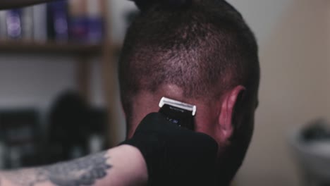 cutting a mans hair short with electric clippers at a barber shop