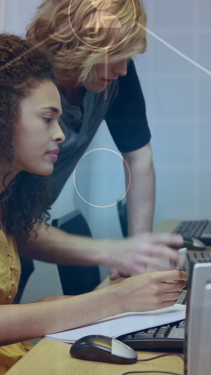 Vídeo vertical: Mulher fazendo anotações no laboratório enquanto homem digita e aponta, iniciando ícones de usuário para treinamento