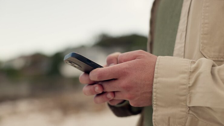 Cellulare, mani e persona che digita all'aperto