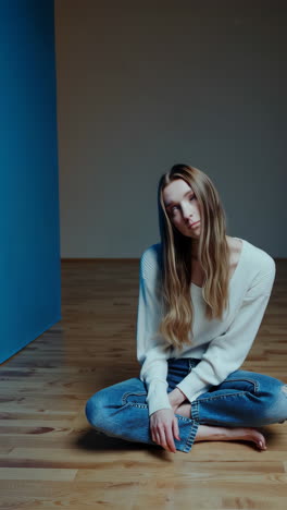 a young woman in pensive poses on a wooden floor