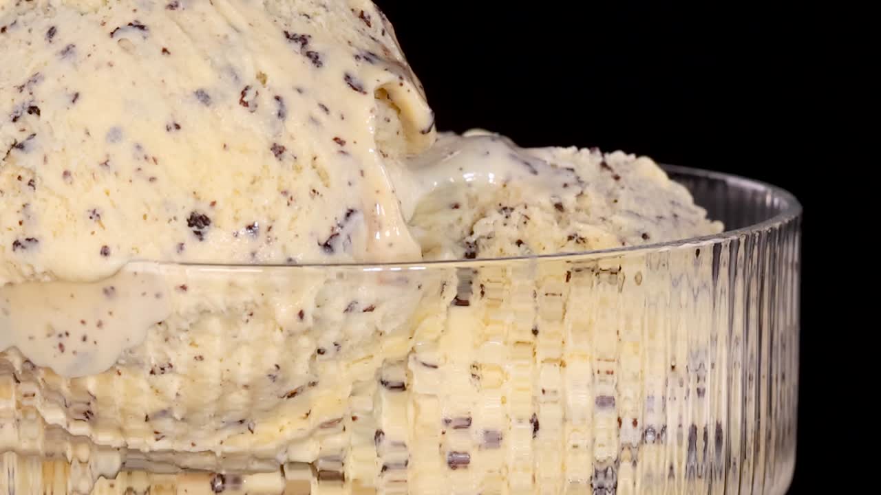 Primo piano di una mano che aggiunge un pezzo di brownie a un gelato con gocce di cioccolato alla vaniglia