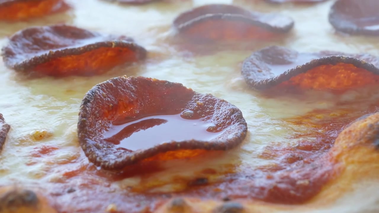 Fırın ısısına tepki veren, yağ salan, peyniri eriten ve kabuğu kızaran kıvrılmış pepperoni dilimleri.