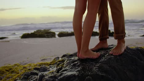 couple standing on rock at beach during sunset 4k