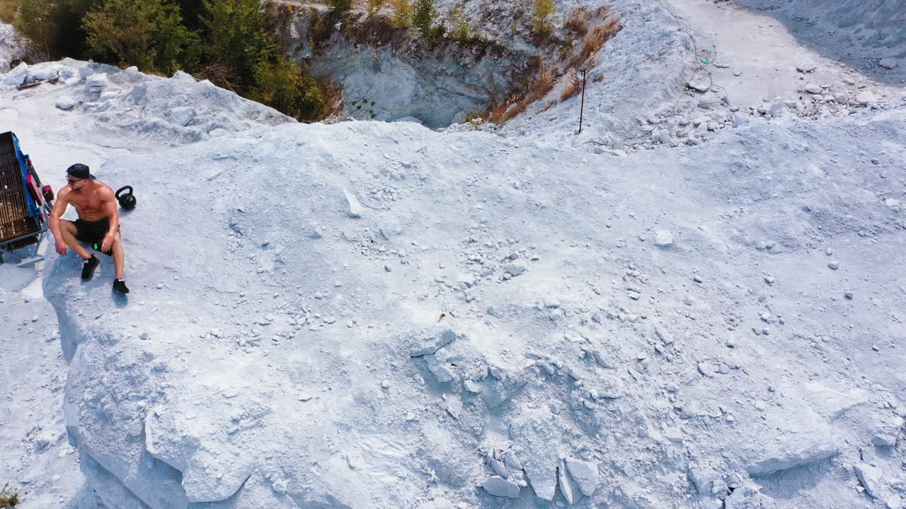 Healthy male resting and drinking water after exercising. Aerial view