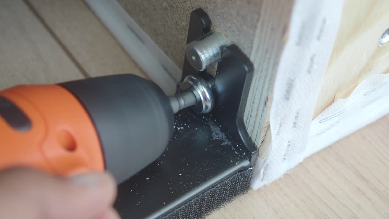 Close-up of Hand Using Electric Screwdriver to Tighten Screw