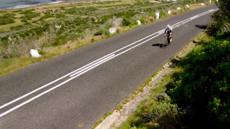 female cyclist cycling on a coastal road 4k