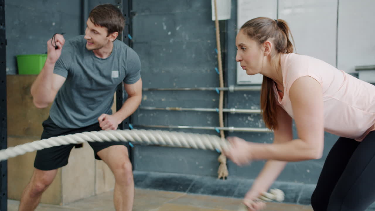 Couple working out with exercise rope in gym