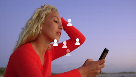 animation mehrerer profil-ikonen, die über einer kaukasischen frau schwimmen, die ein smartphone in der nähe des meeres benutzt.