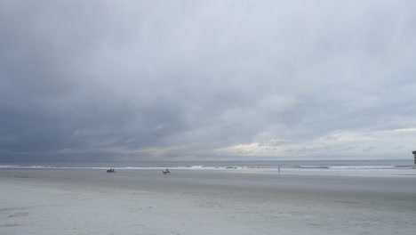 Storm-brewing-above-wide-shot-of-beach-waves-breaking-in-distance