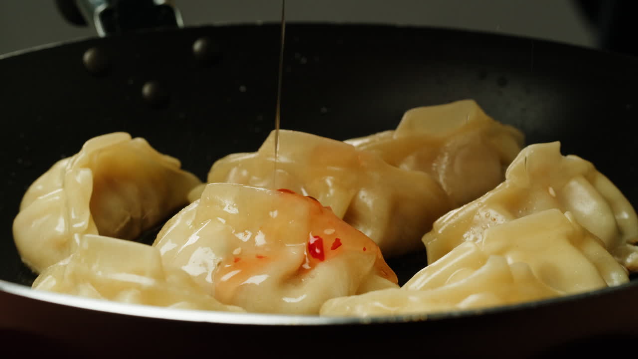 Drizzling Sweet Chili Sauce on Hot Dumplings in a Frying Pan
