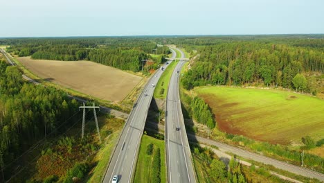 4k static aerial view of 4-lane highway with cars and trucks passing both directions during hazy summer morning sunlight