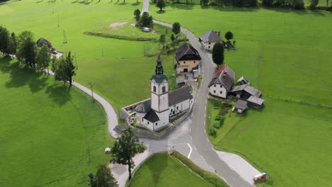 Aerial-view-of-church-with-cemetery,-Jezersko,-Slovenia,-a-small-rural-town-in-European-Alps