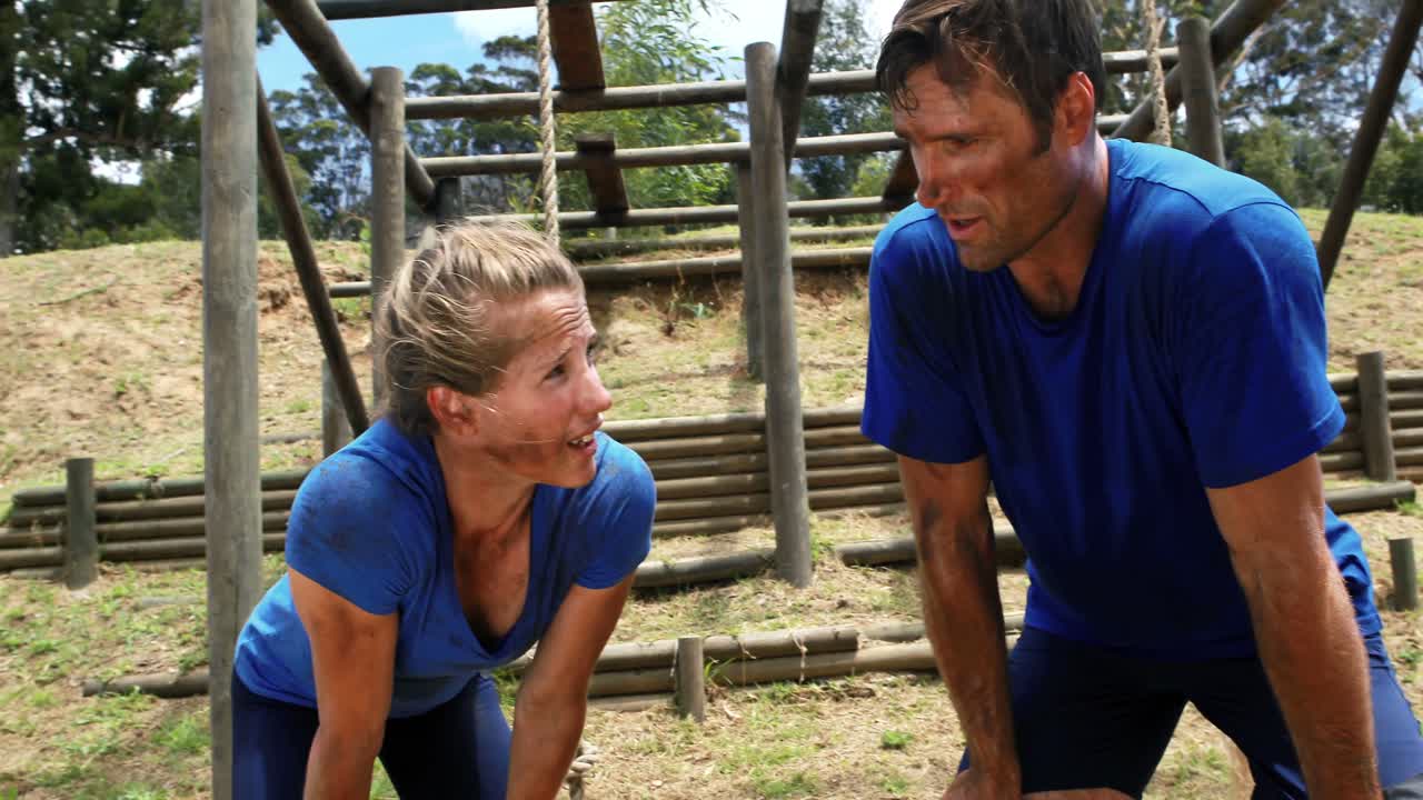 hombre y mujer en forma relajándose después del entrenamiento durante una carrera de obstáculos