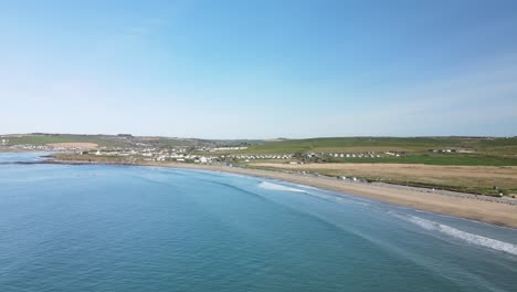 una filmación aérea, siguiendo una larga playa de arena con olas gentiles en un día soleado en irlanda
