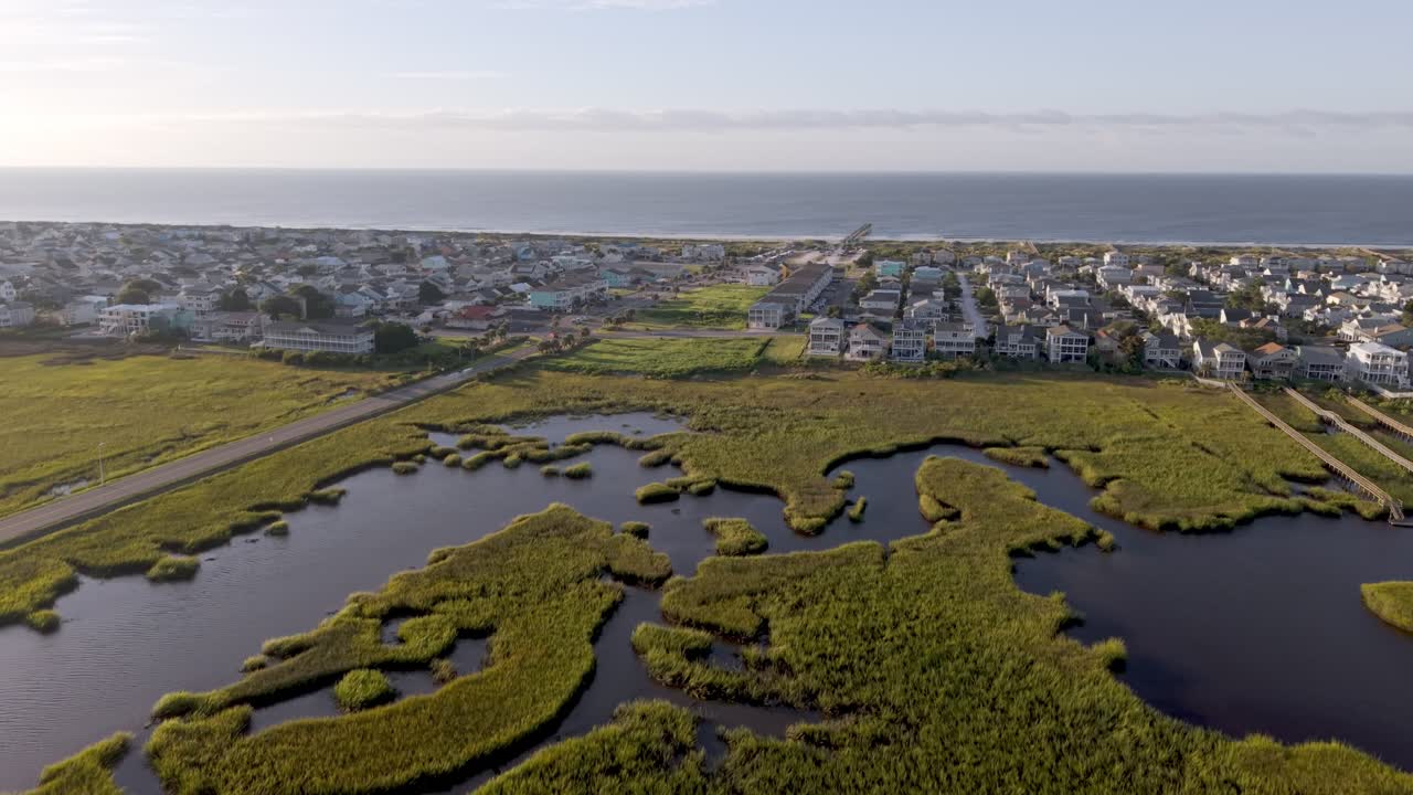 Aerial of sunset beach rising from the cordgrass to reveal beachfront homes