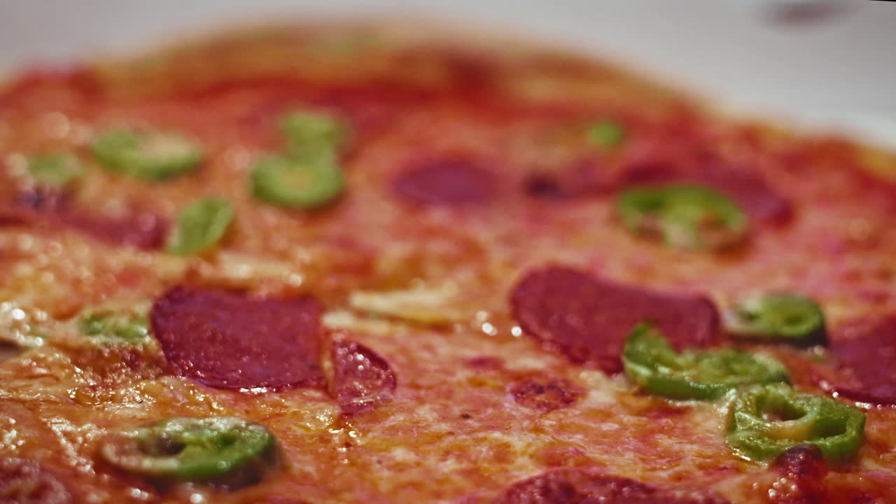Primo piano di una pizza a domicilio fresca, calda e piccante con jalapenos e salame
