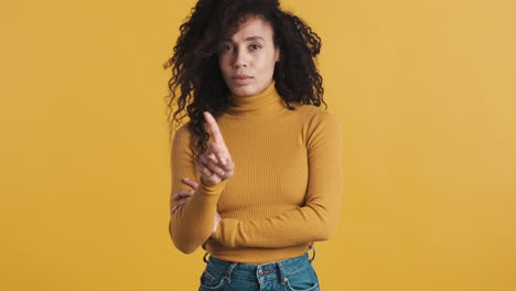 una mujer afroamericana segura de sí misma sobre un fondo naranja.