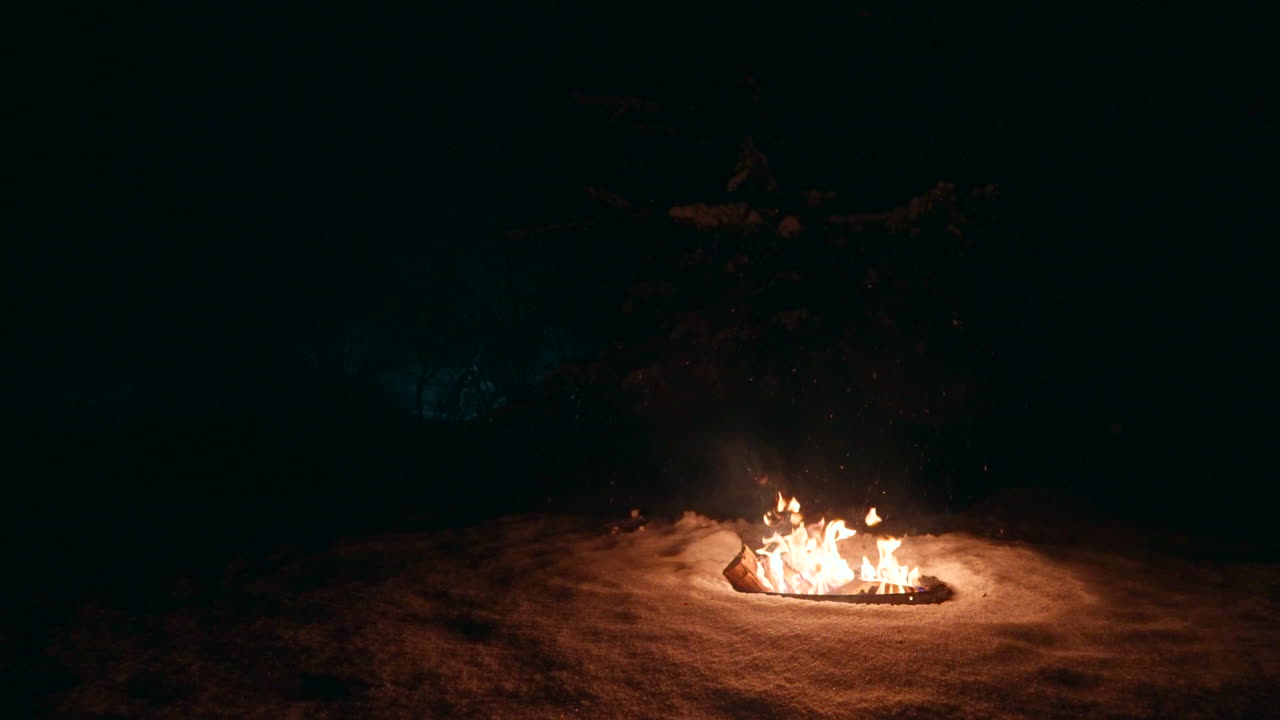 cámara lenta, fuego de tronco ardiente, copos de nieve cayendo, paisaje nocturno