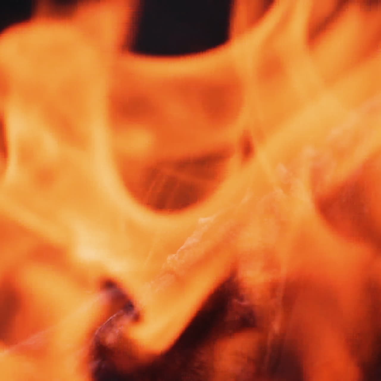 Close-up blur bright flame. Vivid flame of bonfire on dark background. Detailed motion of yellow and red fire. Slow motion.