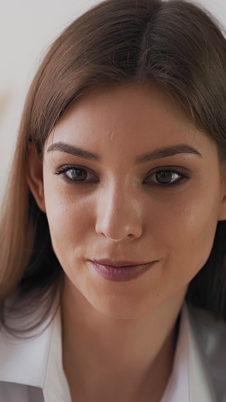 Concentrated young woman artist with long hair looks at canvas drawing new painting on light background in art studio extreme close view