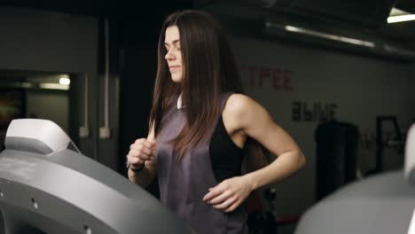 attractive young sportive girl with long brunette hair is very concentrated while running on threadmill. healthy lifestyle, fitness, active leisure time and wellbeing.