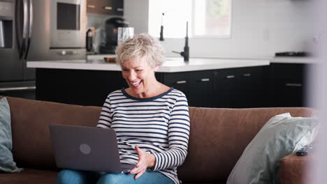 senior woman video calling on a laptop waving at screen