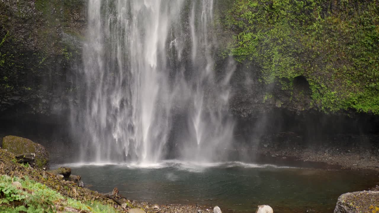 Slow motion landscape of secluded running waterfall Multnomah Falls water stream river surrounded by mossy rocks Oregon forest Portland USA America nature travel tourism