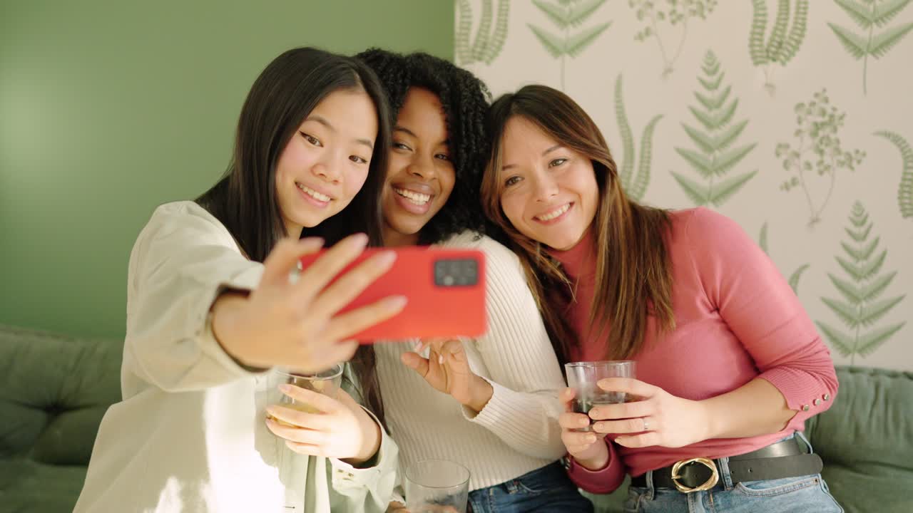 Multi-ethnic friends smiling taking a selfie indoors