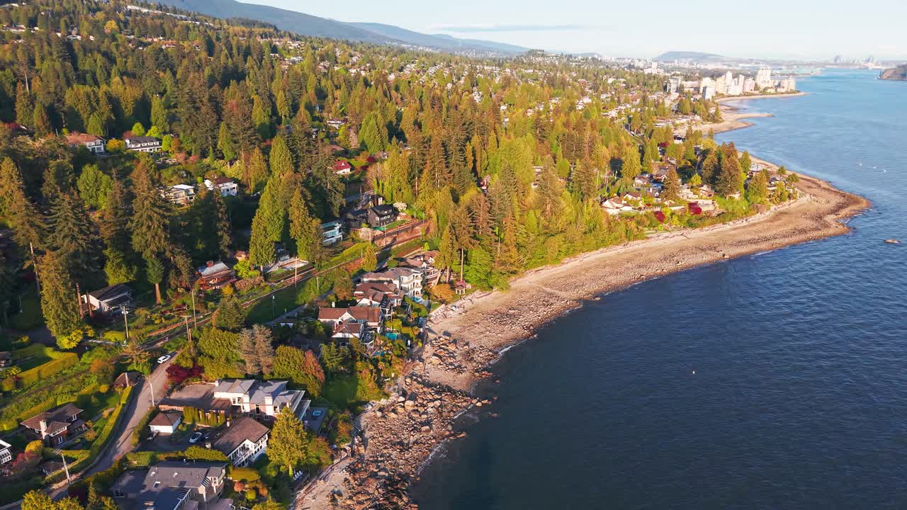 A golden hour shot of a Luxury neighborhood surrounded by lush green trees with calm blue waters on the coastline
