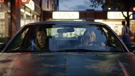 tension builds inside the vehicle as two individuals remain focused on their destination with a bank in the background illustrating a potential heist setup