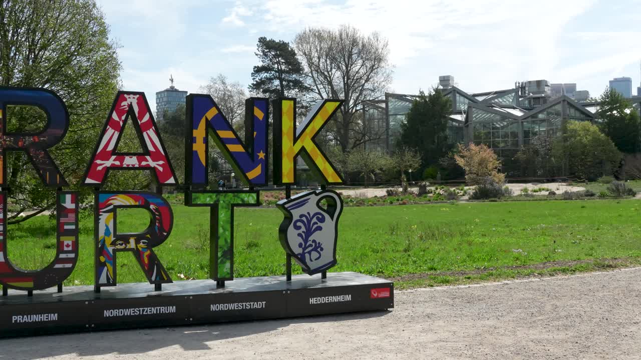 Installazione colorata del cartello della città di Francoforte nel Palmengarten con parco verde e alberi sullo sfondo durante il giorno