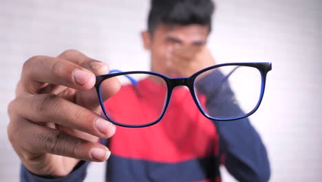 teenager holding his glasses, eyes tired