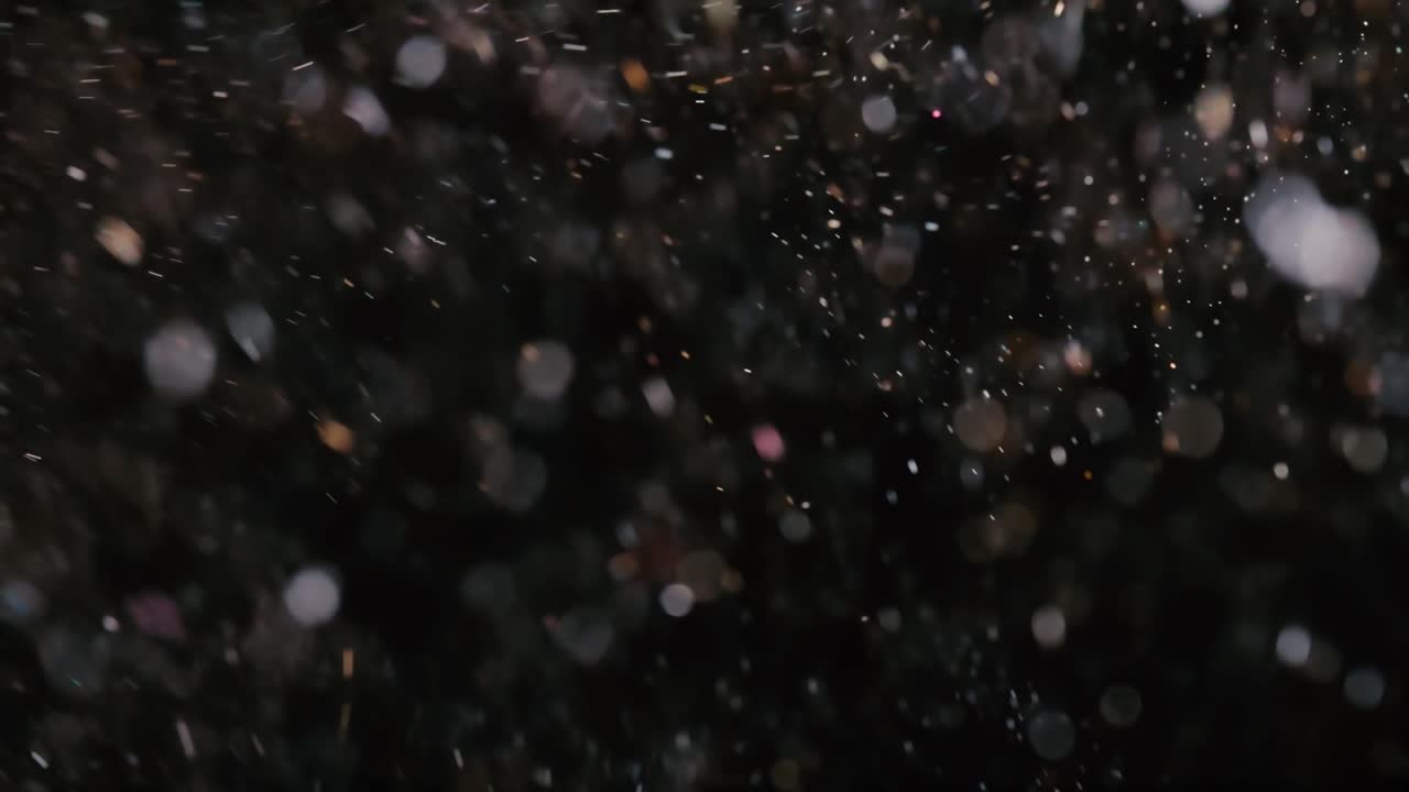 Kelluvia abstrakteja bokeh-hiukkasia tummalla taustalla.