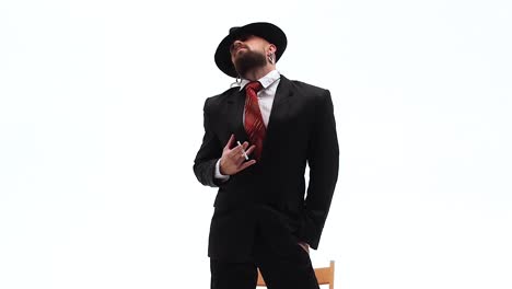 a man in a black suit and fedora smoking and posing on a white background