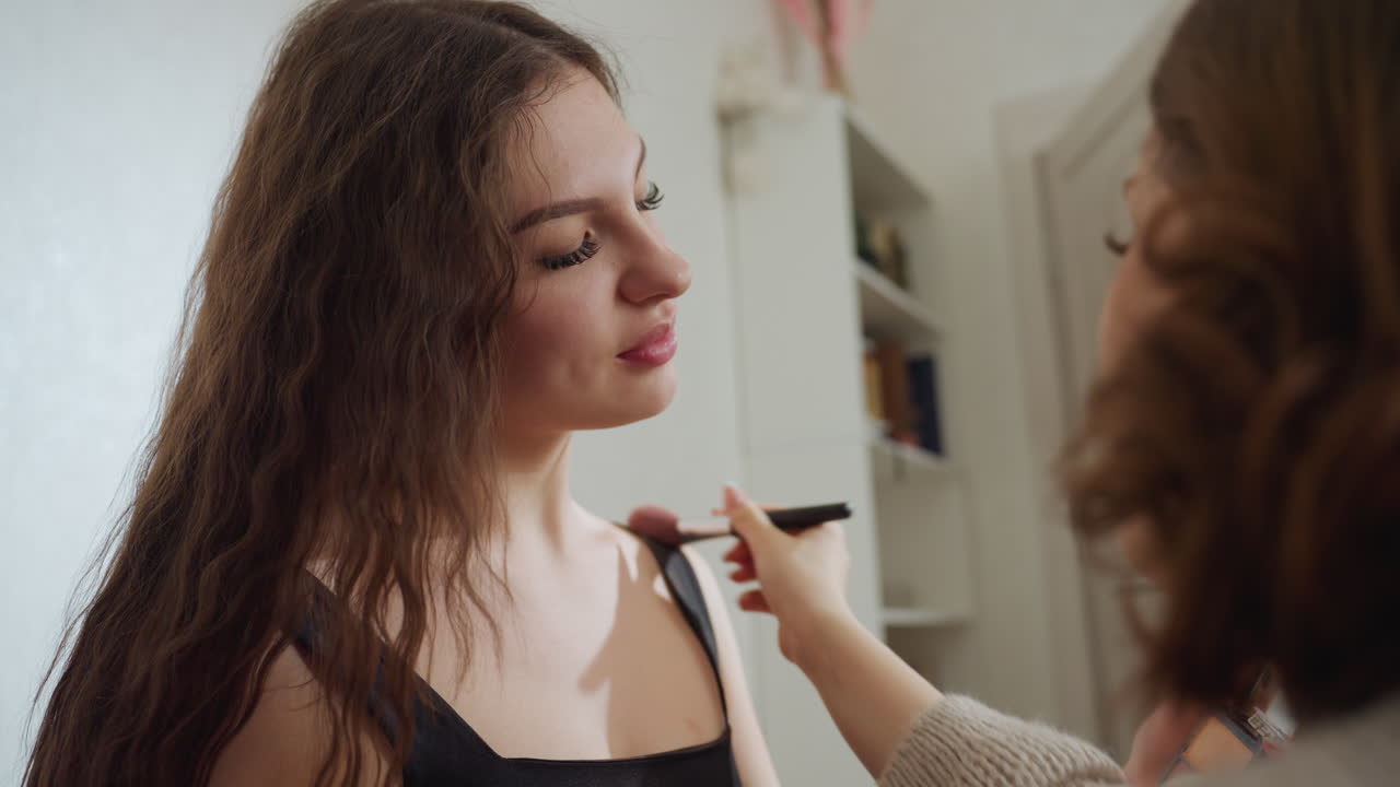 Professional Makeup Artist Prepares Model, Elegant Woman Receiving Makeup Touch Up Before Photo Shoot, Female Model Getting Cosmetic Blending Done With Brush Prior To Photography Session