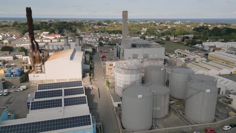 Short-drone-flight-between-power-station-chimneys-heading-north-with-views-across-to-north-coast-of-Guernsey-on-bright-day