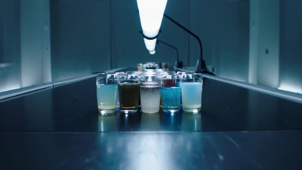 Conveyor activating, moving cluster of glass jars toward viewer for inspection under tubular light