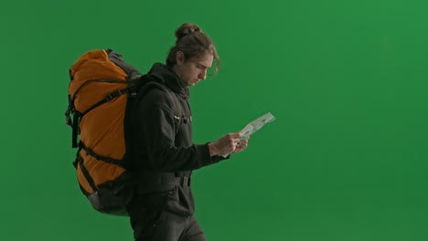 man with backpack looking at map on green screen