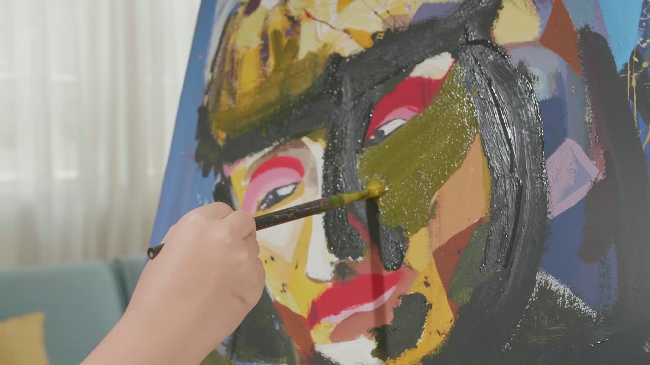 cerca de una niña de una mano sosteniendo un pincel y pintando la cara de una niño en el lienzo