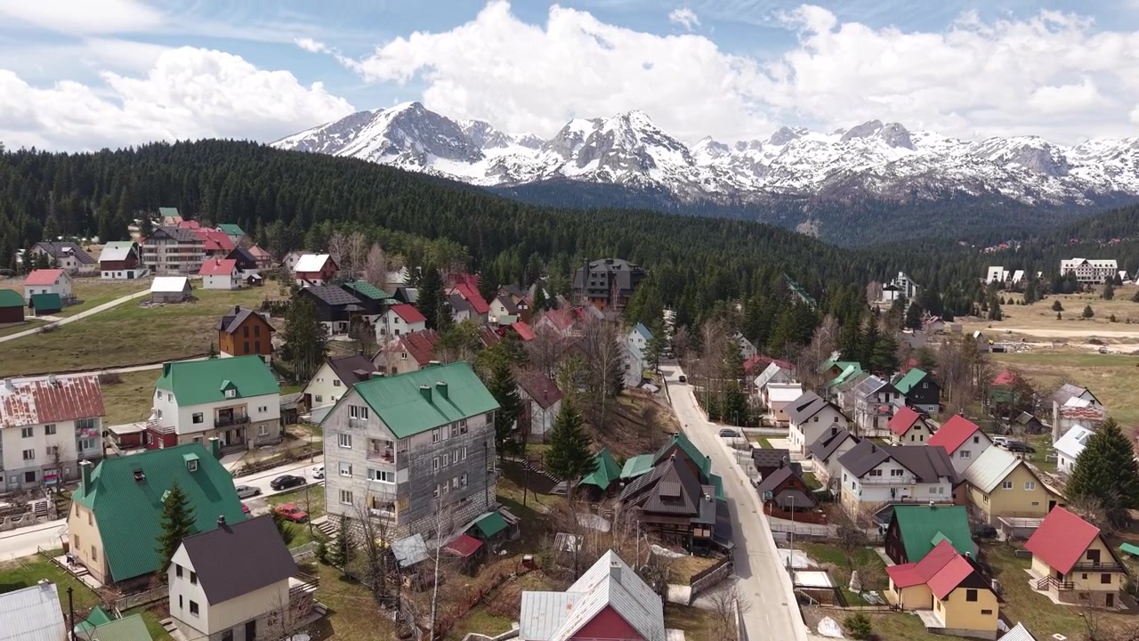 Ripresa con drone della città di Zabljak sotto le cime innevate del monte Durmitor, Montenegro, stazione sciistica in estate.