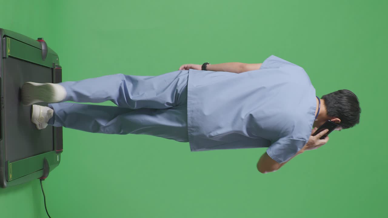 병원에서 녹색 화면 배경에서 는 동안 스마트폰으로 말하는 스테토스코프를 가진 아시아 남성 의사